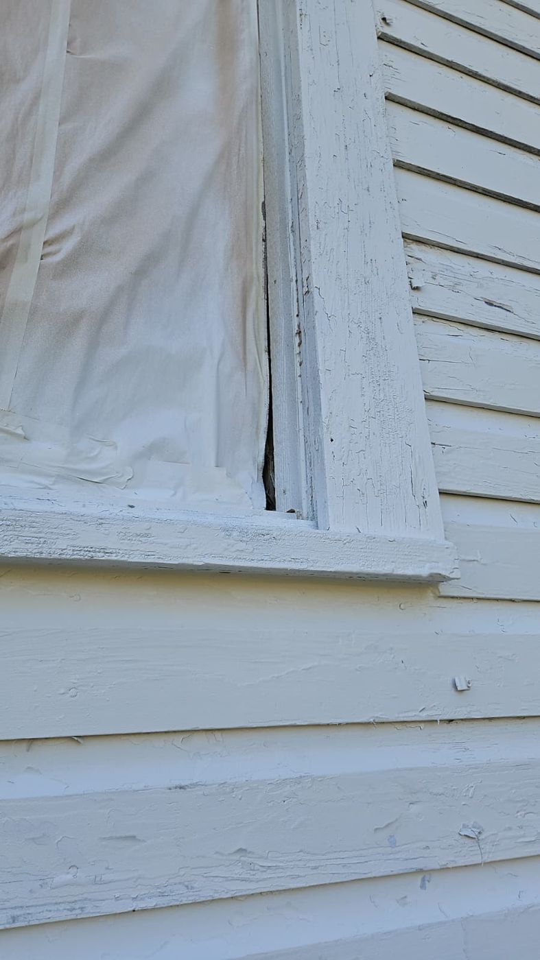 Exterior window covered with plastic beside siding
