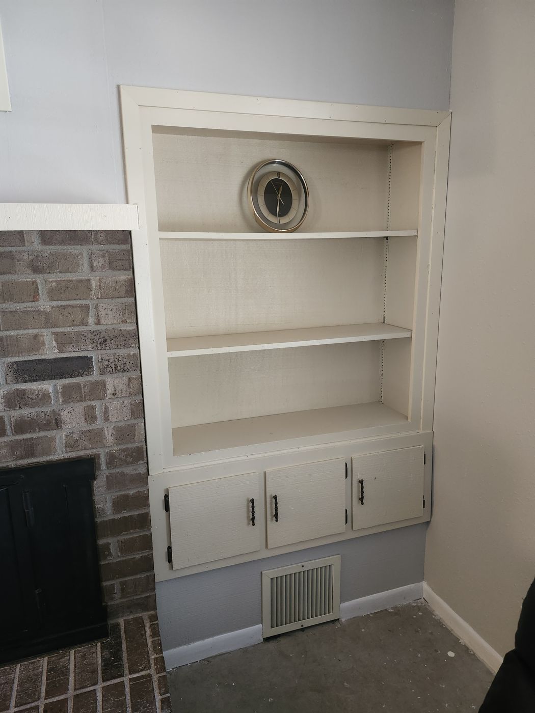 White painted built-in shelving beside a brick fireplace